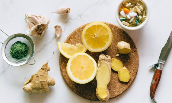 Flat lay of natural remedies including lemon, ginger, and garlic alongside pills.